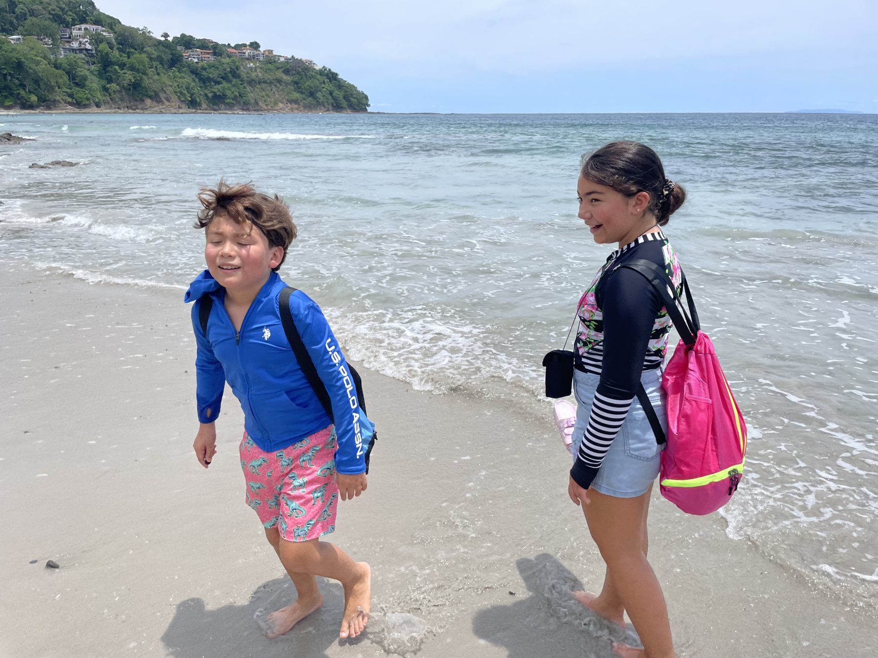 Children enjoying the white-sand beach a short walk from the Playa Mantas lot — best places to buy near Jaco Beach, Costa Rica