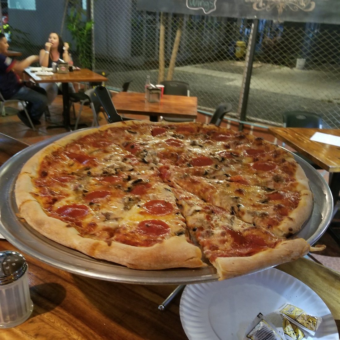 Big New York-style pepperoni pizza on a silver pan at The Pizza Shop in Jacó