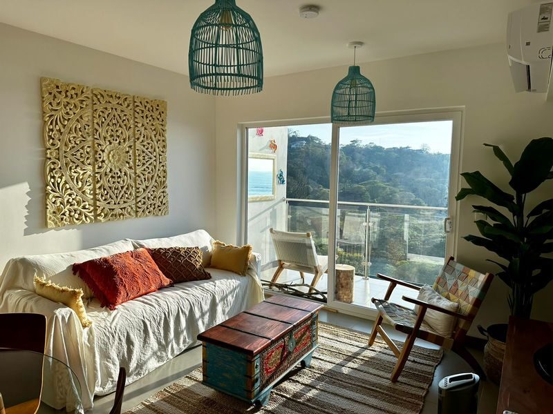 Bright living room with glass balcony doors and ocean views in a Playa Blanca apartment — Jaco Beach real estate, best properties near Jaco Beach