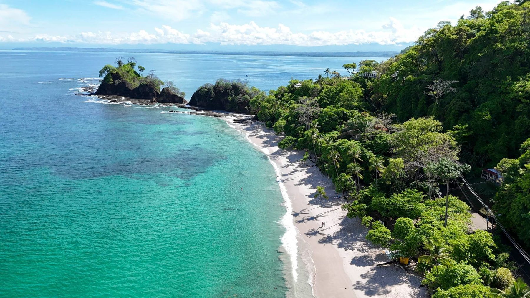 Aerial view of Punta Leona beach near Jacó, Costa Rica — white sand coves surrounded by jungle and almendro trees
