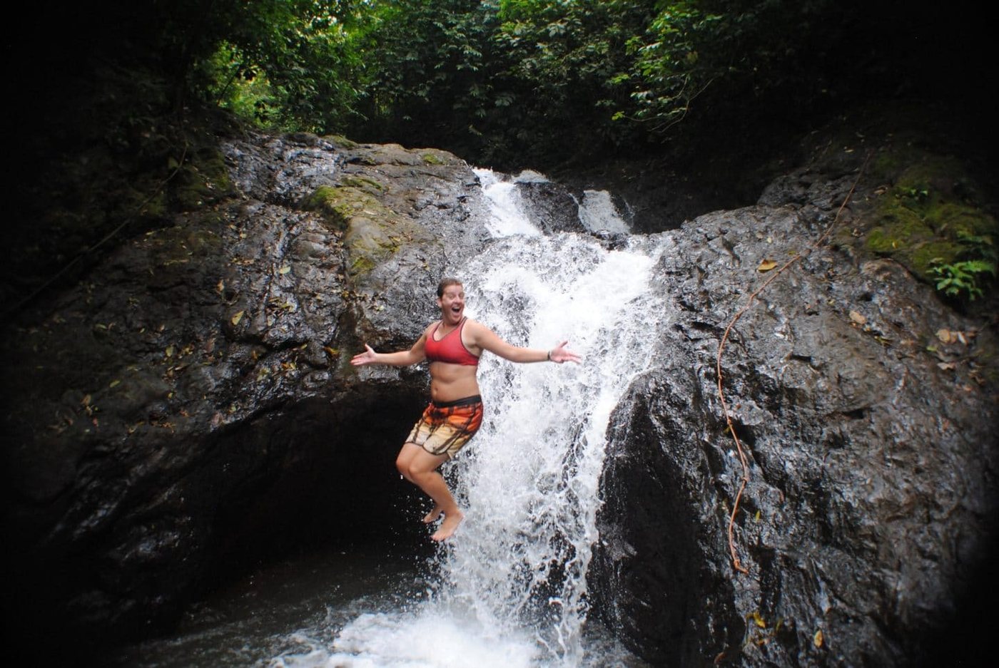 Climber on the rocks beside a jungle waterfall