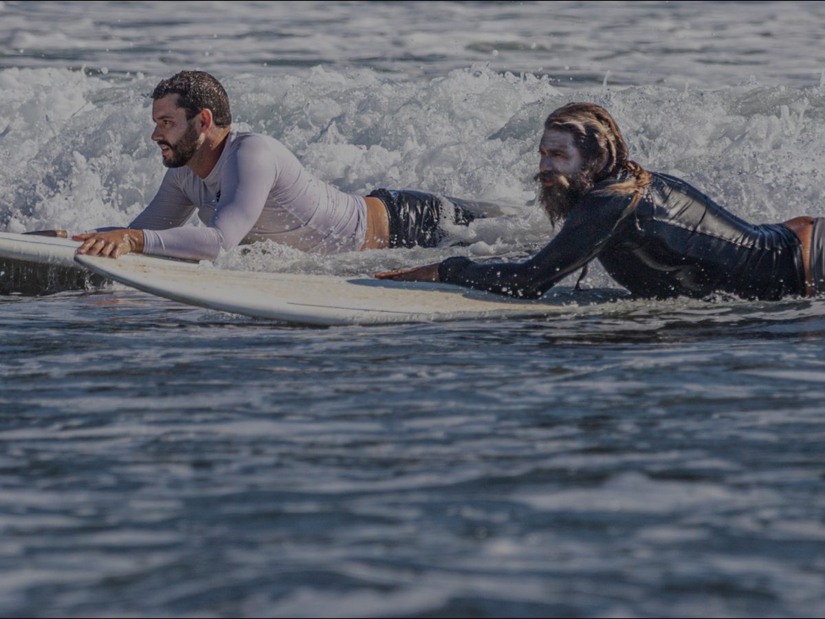 Surf instructor and student paddling out at Jacó Beach