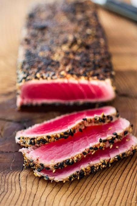 Sesame-crusted seared ahi tuna sliced on a wood board, prepared by a private chef in Jaco Beach