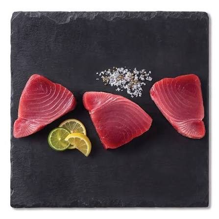 Fresh raw ahi tuna steaks on slate with lemon and salt, ready to grill or serve raw in Jaco Beach